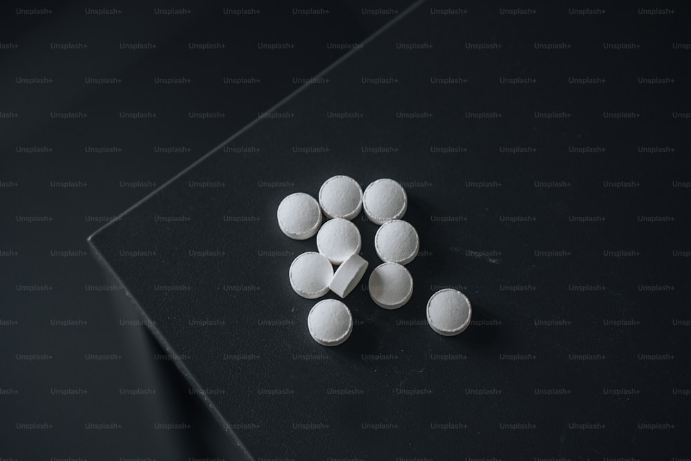 a pile of white pills sitting on top of a black table