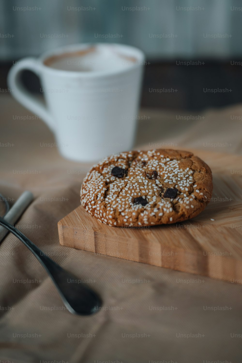 a cookie sitting on top of a wooden cutting board next to a cup of coffee