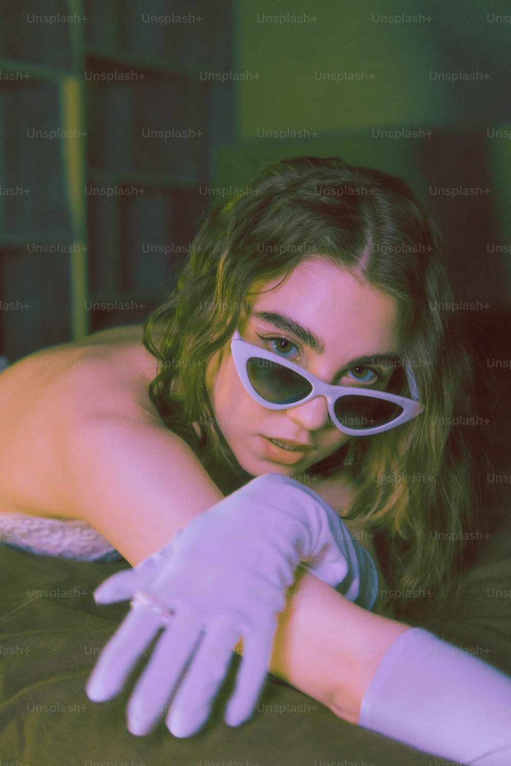a woman in white gloves and sunglasses laying on a bed