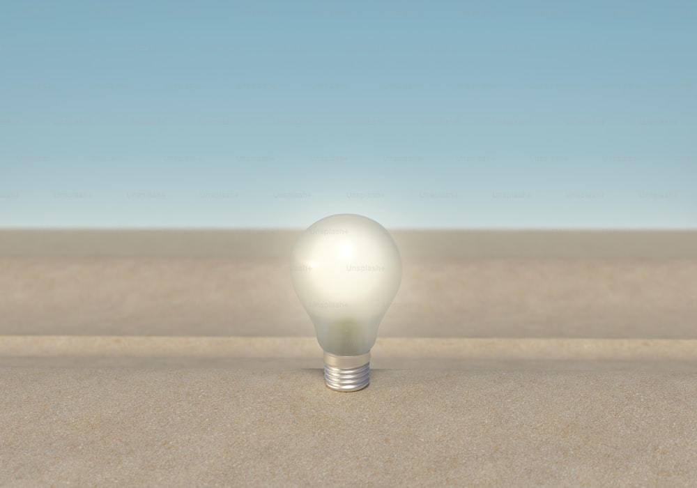 Eine weiße Glühbirne, die auf einem Sandstrand sitzt
