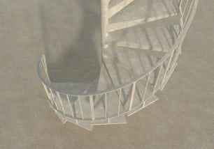 Una escalera de caracol blanca en medio de una zona arenosa