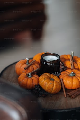 a wooden table topped with a candle and pumpkins