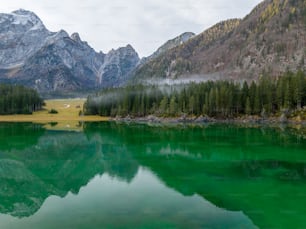a green lake surrounded by mountains and trees