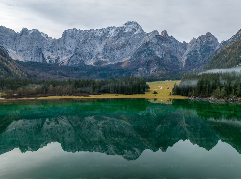 a mountain range is reflected in the still water of a lake