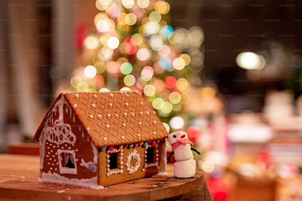 Ein Lebkuchenhaus mit einem Weihnachtsbaum im Hintergrund