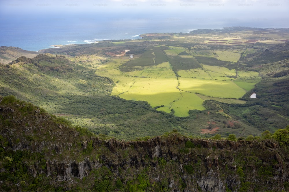 a scenic view of a green valley and the ocean