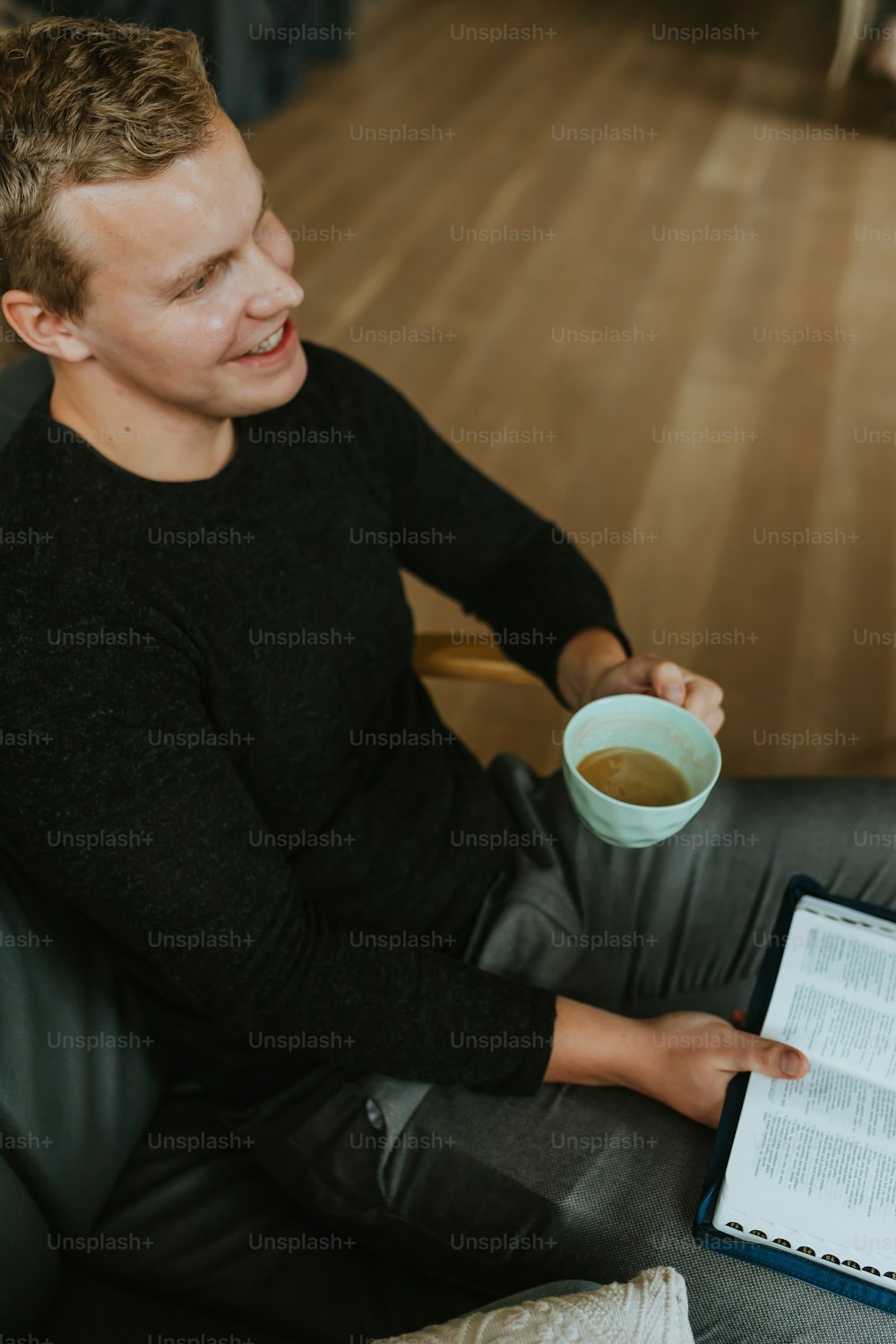Una persona sentada en el suelo y sosteniendo una taza de té