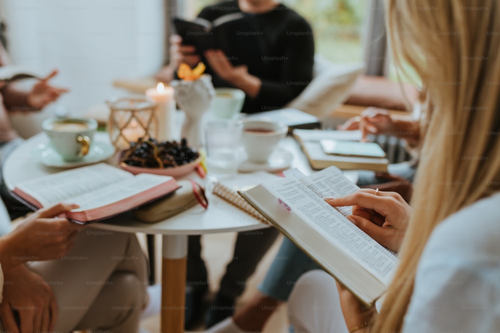 a group of people sitting around a table with books and cups