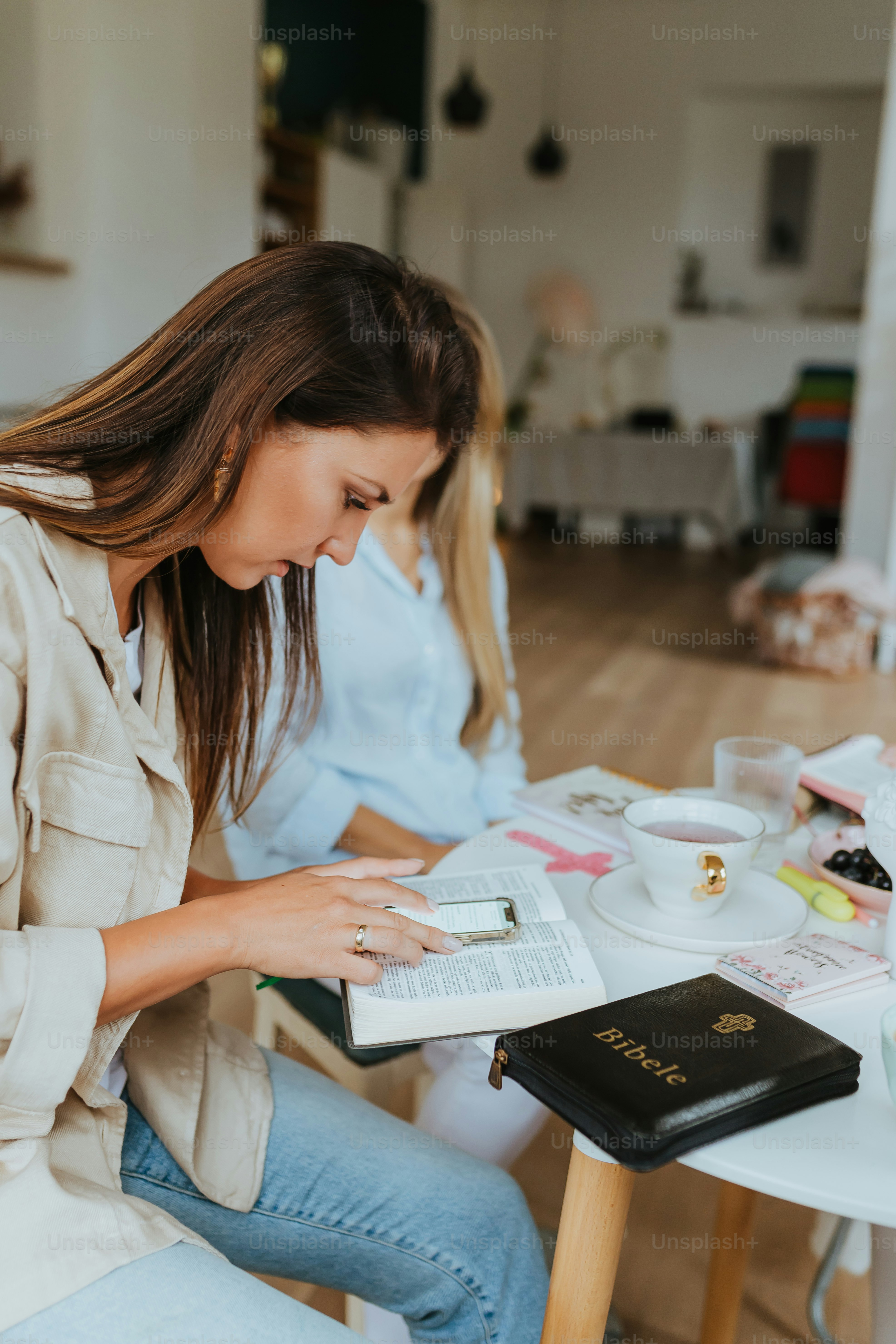 a woman sitting at a table looking at a book