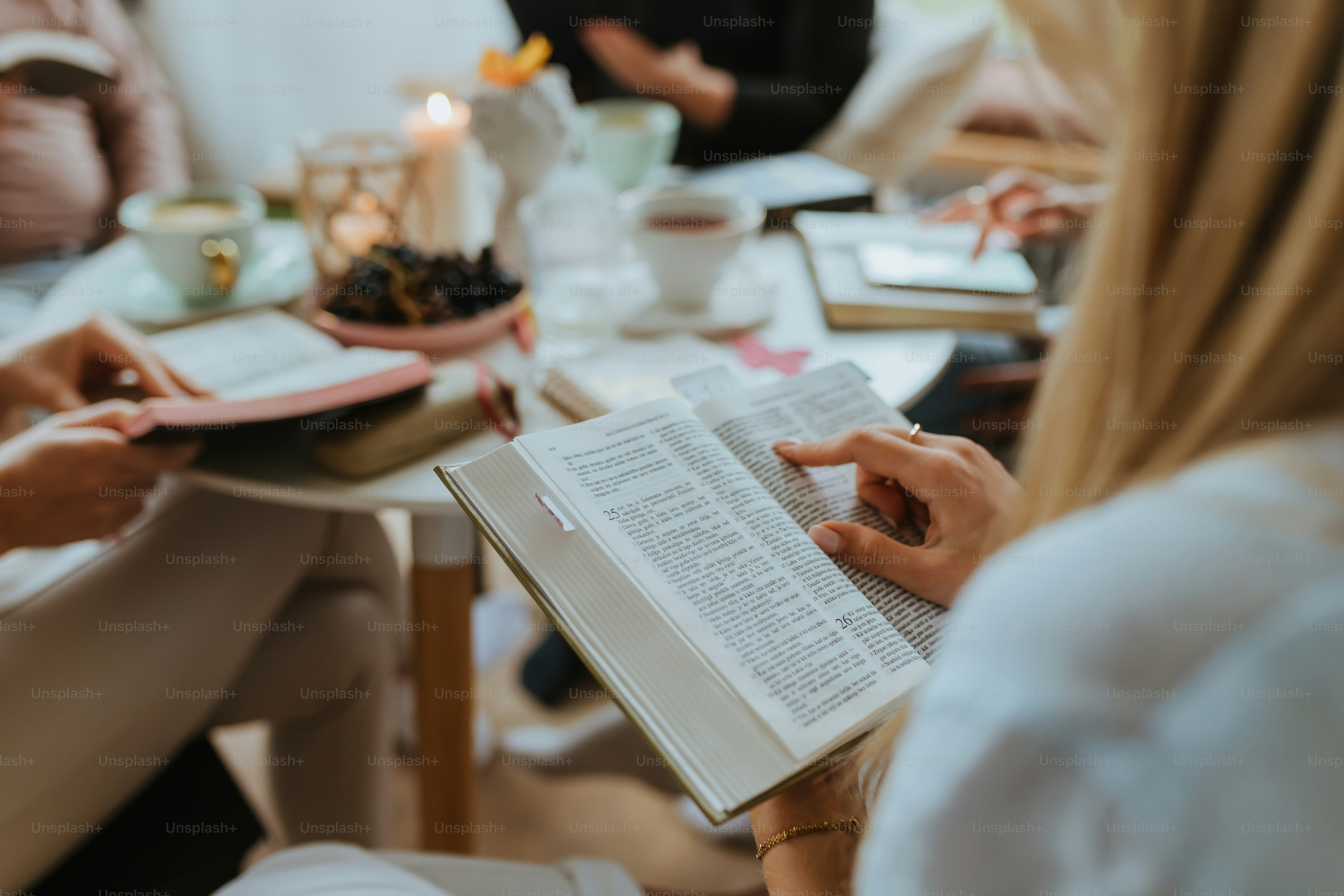 a group of people sitting at a table reading a book