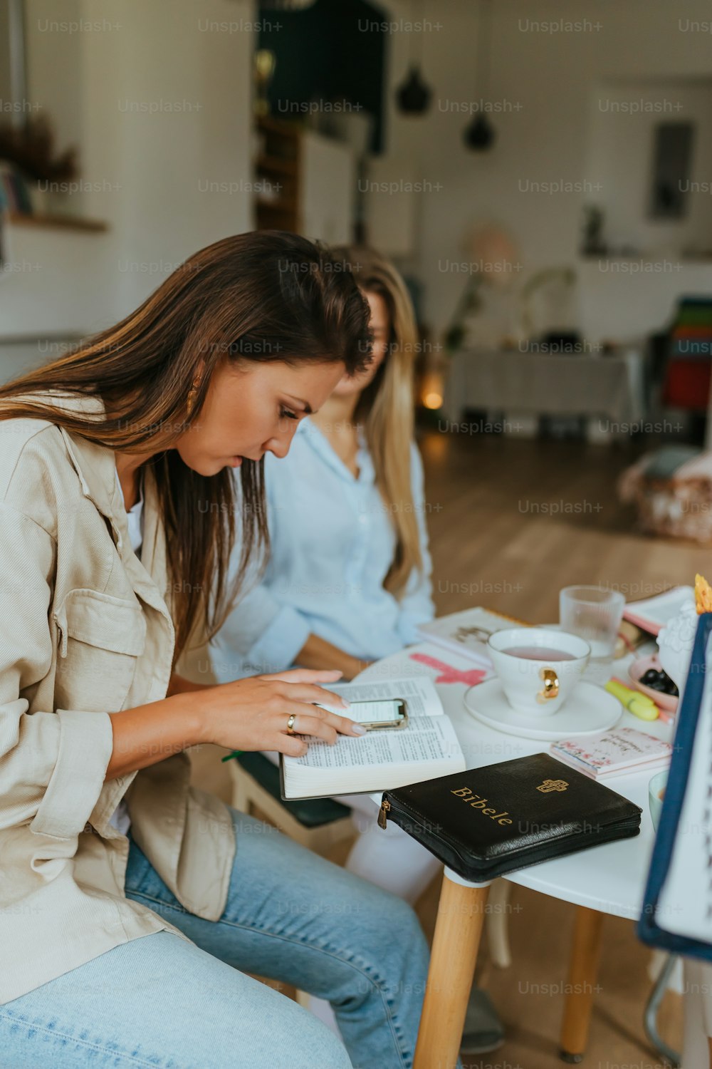 a woman sitting at a table reading a book