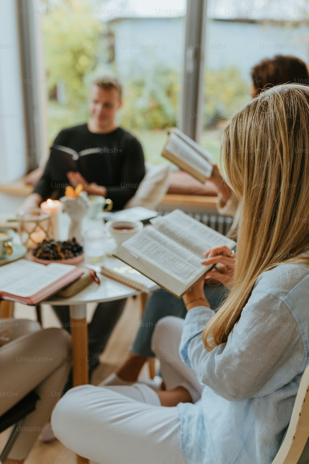 a group of people sitting at a table reading books