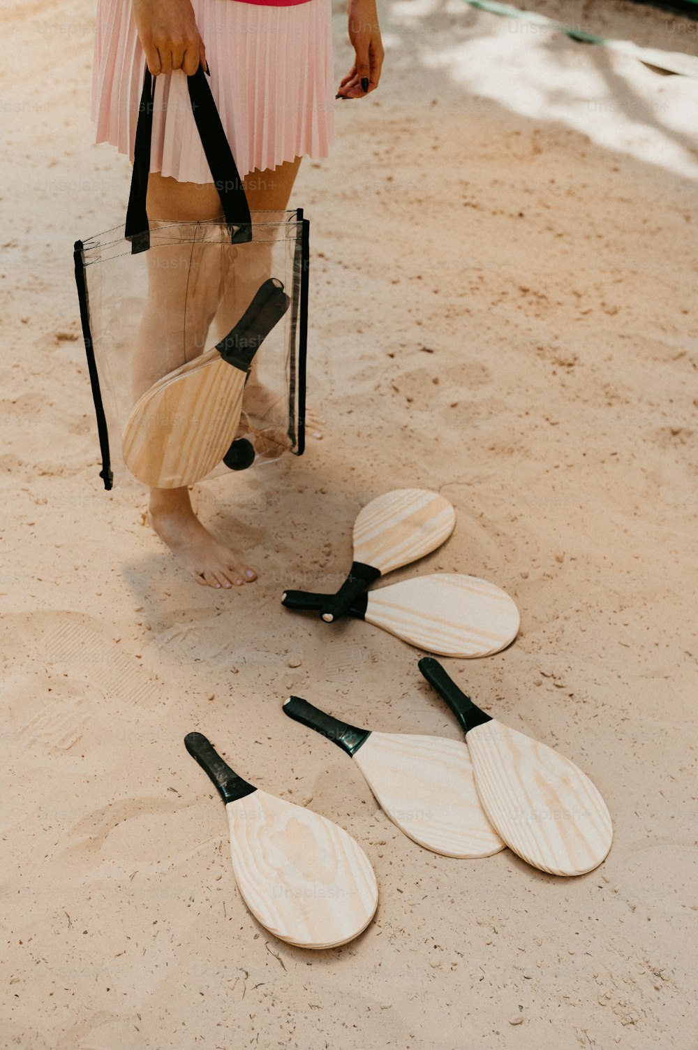a woman standing on the sand with four paddles in front of her