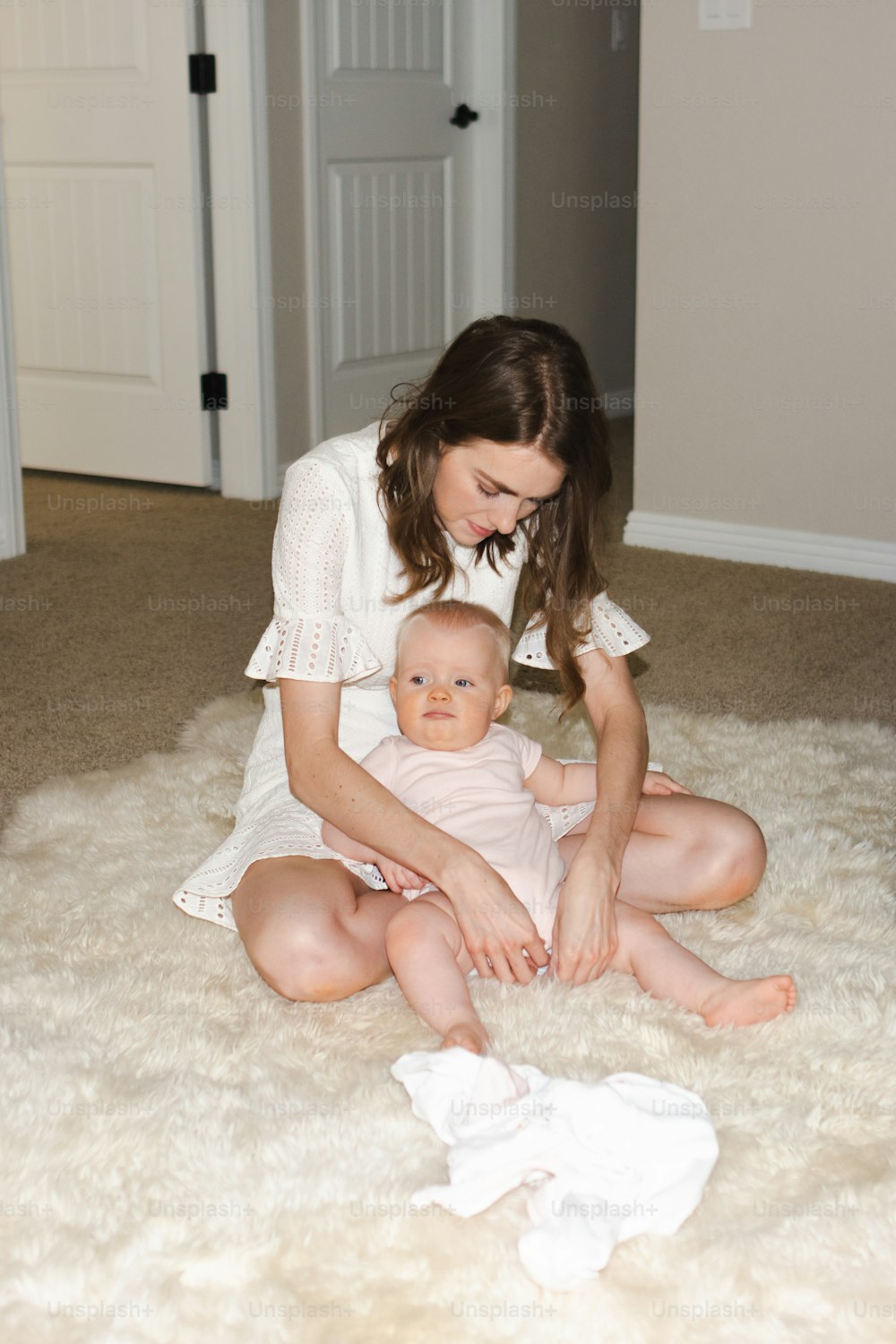 a woman sitting on the floor holding a baby