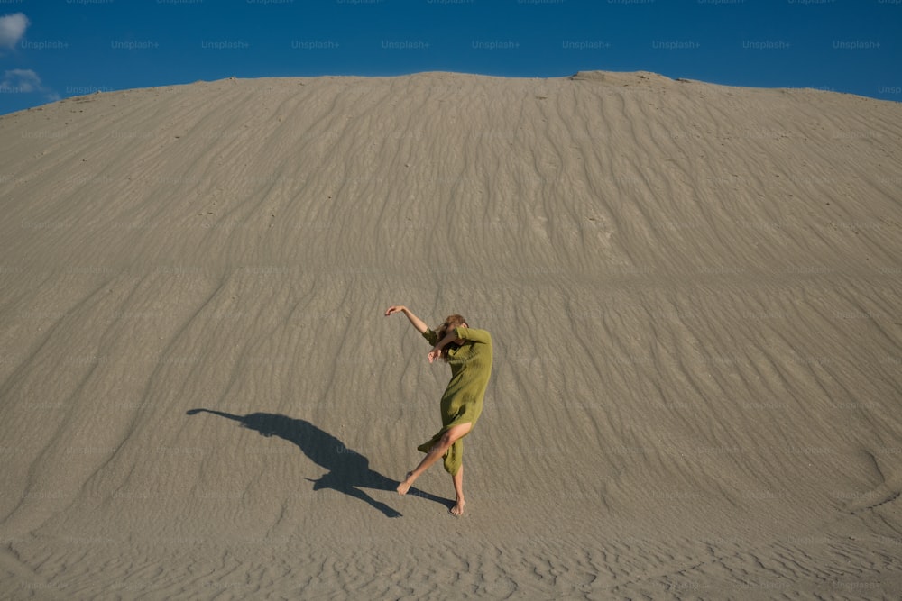 a woman in a green dress standing in the sand