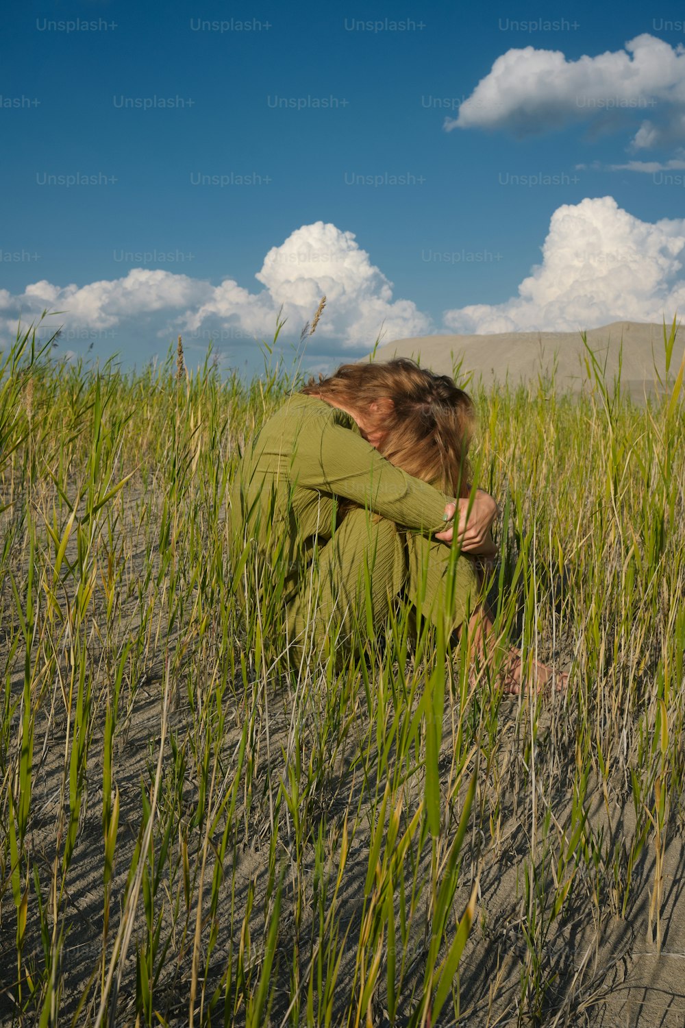 uma mulher ajoelhada em um campo de grama alta