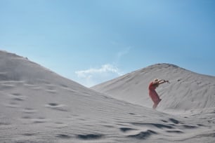Une femme en robe rouge debout dans le sable