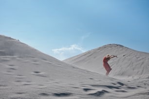 a woman in a red dress standing in the sand