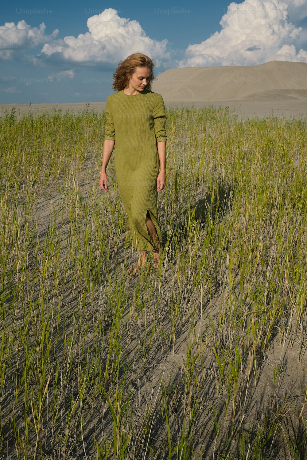 a woman walking through a field of tall grass