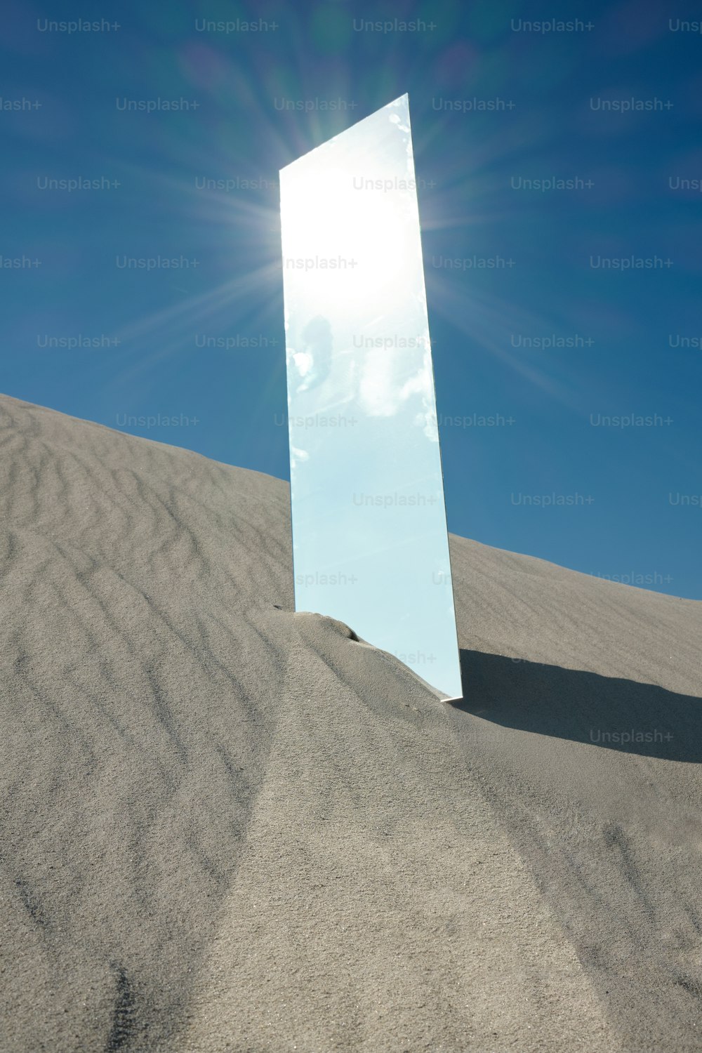 a large mirror sitting on top of a sandy hill