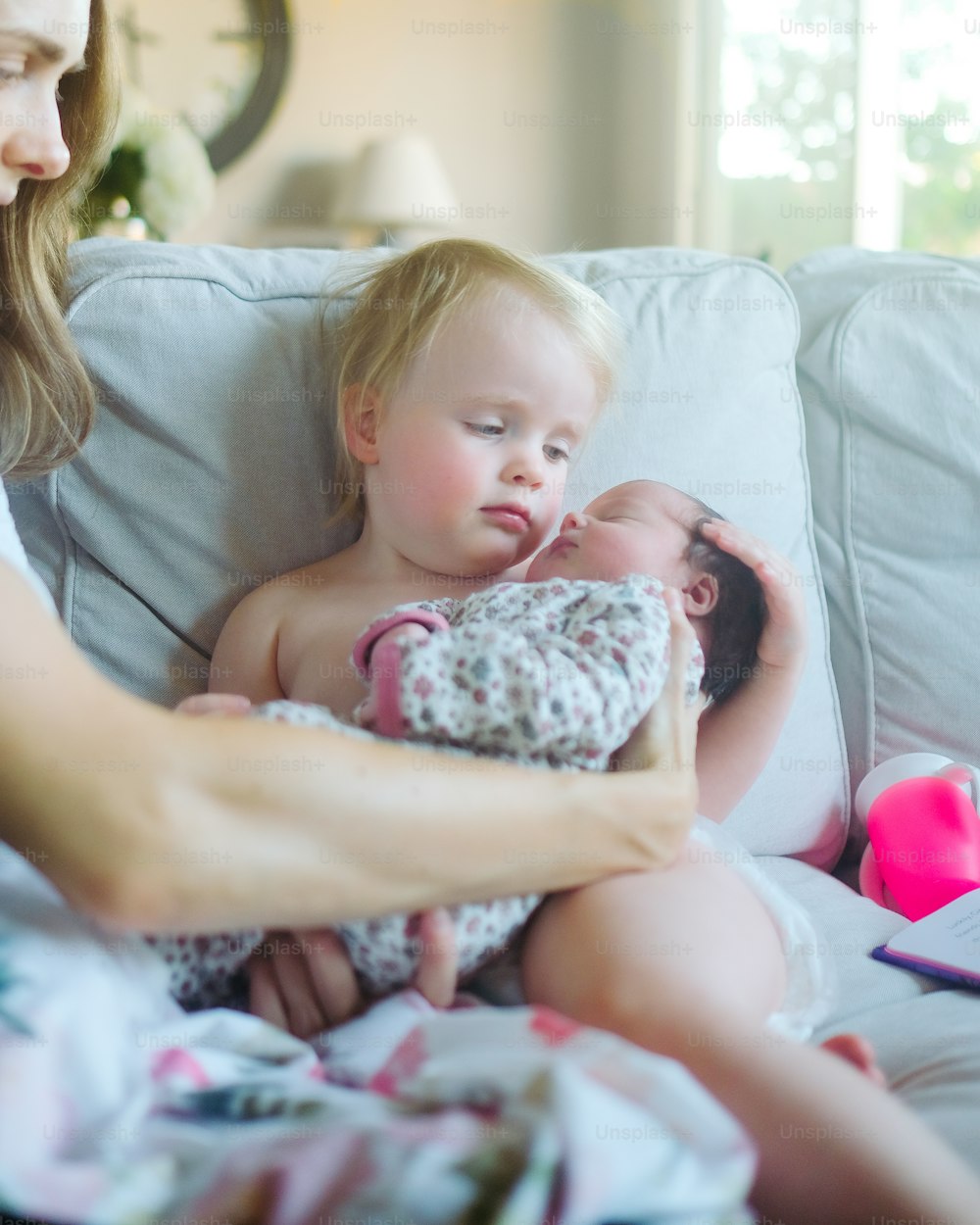 a woman holding a baby on top of a couch