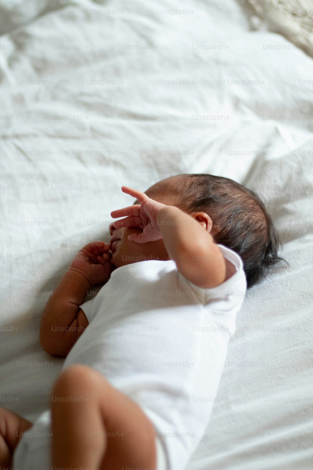 un bébé allongé sur un lit pointant quelque chose