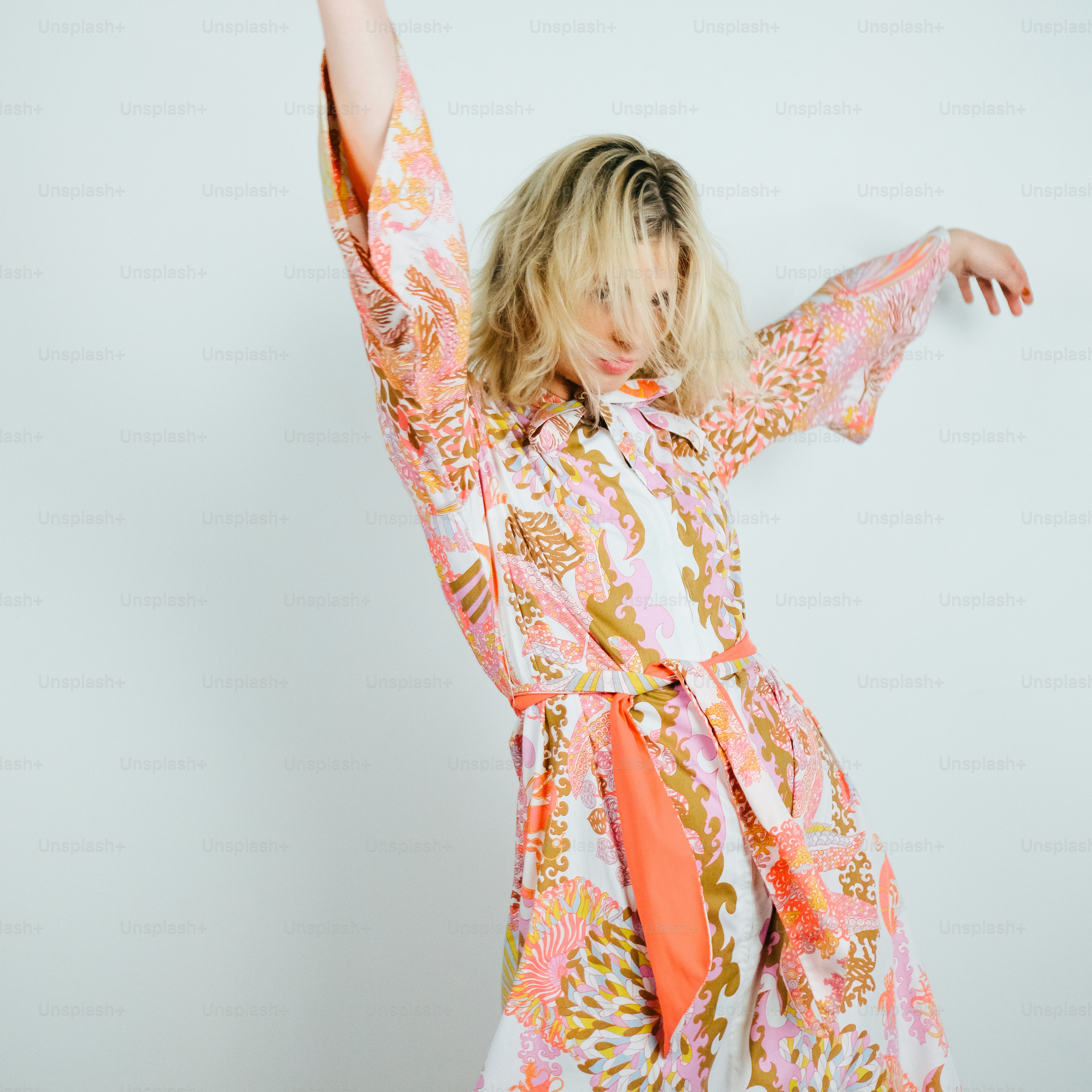 Una mujer con un vestido colorido sosteniendo sus brazos en alto
