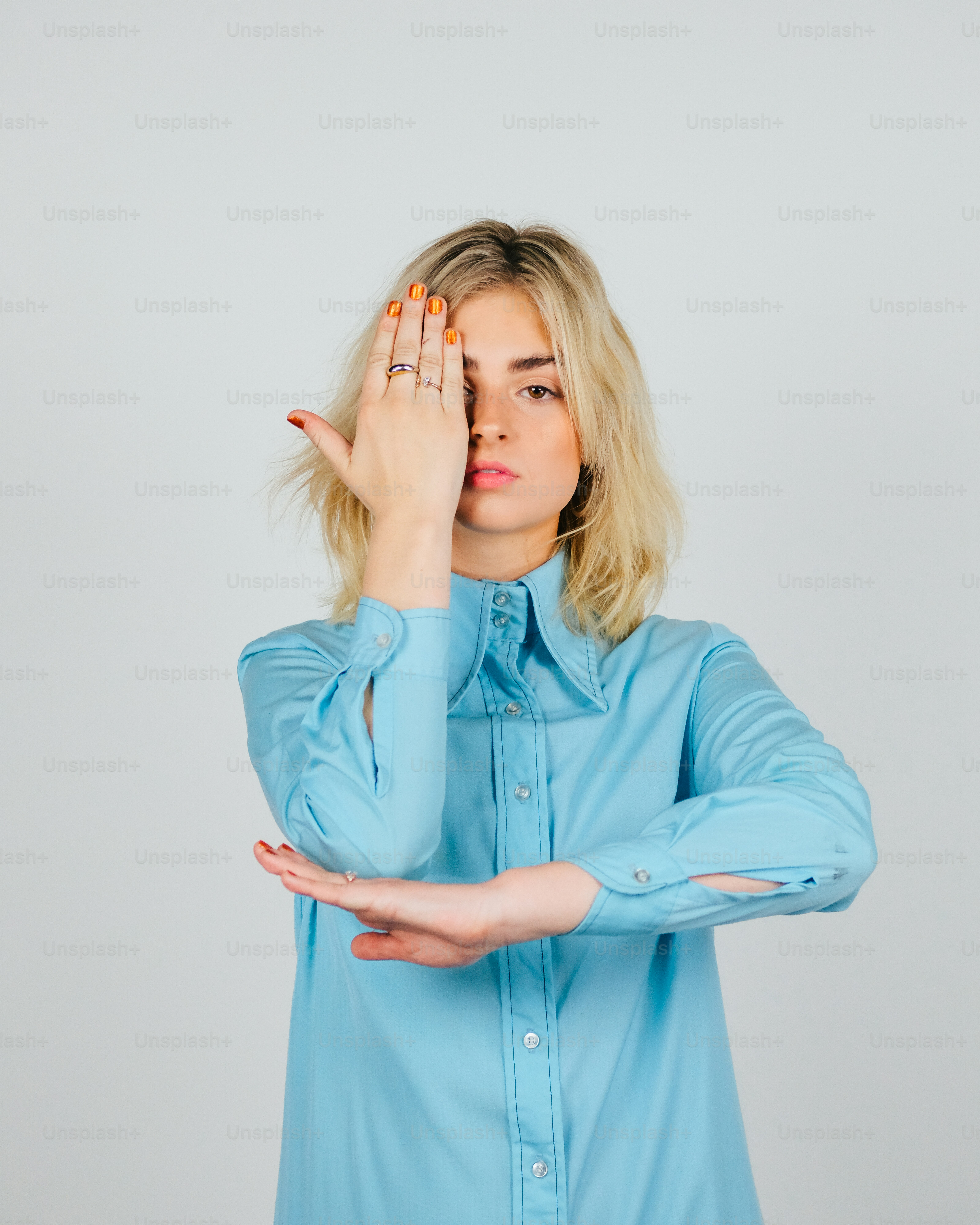 Una mujer con una camisa azul sosteniendo sus manos hacia su cara