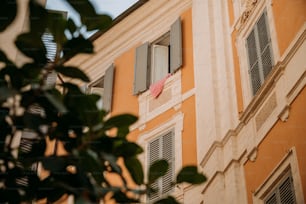 an orange building with shutters and a pink umbrella