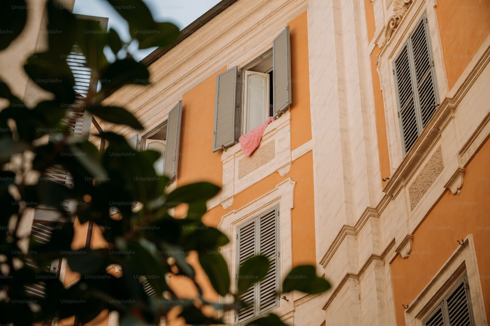an orange building with shutters and a pink umbrella