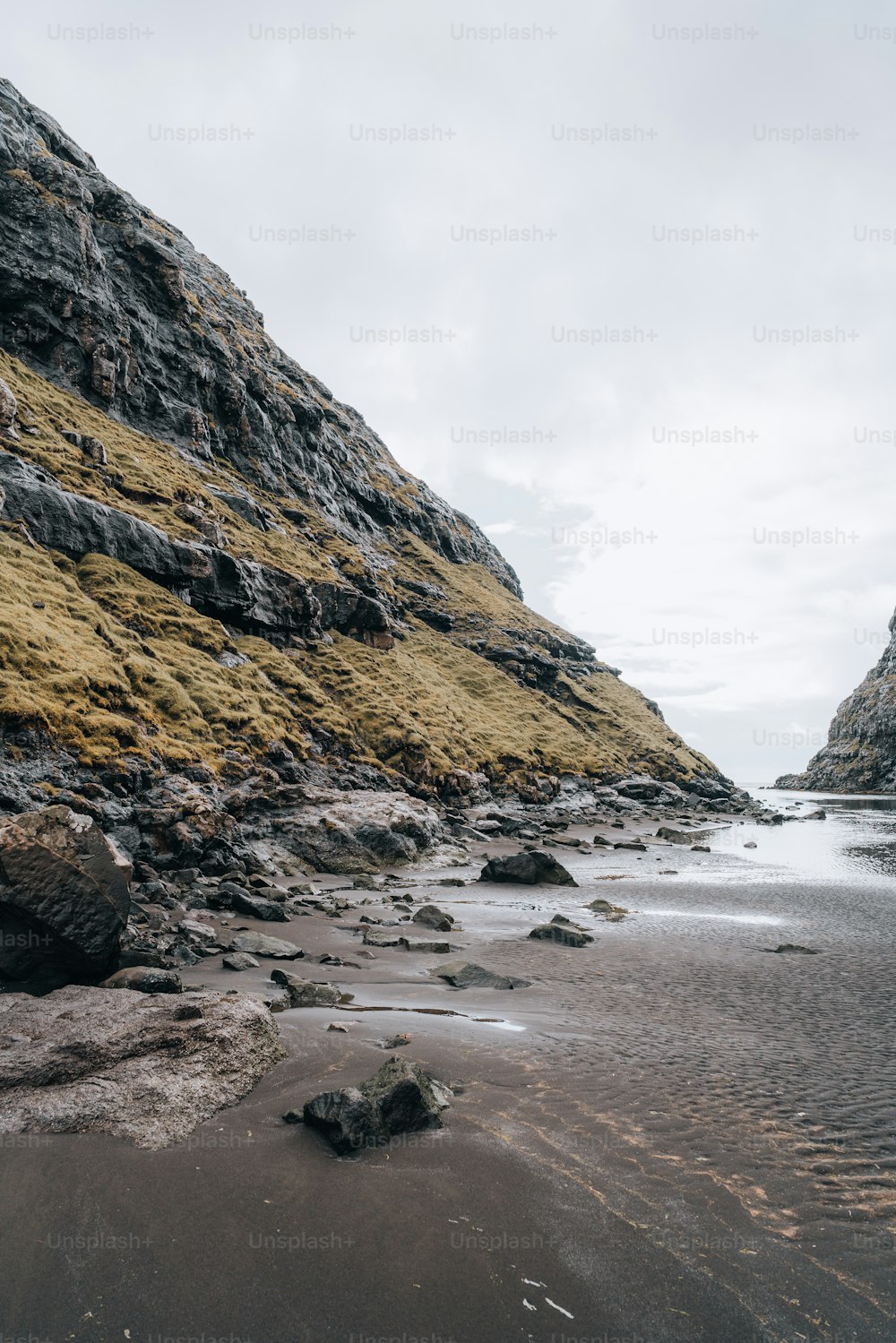 a sandy beach next to a rocky cliff