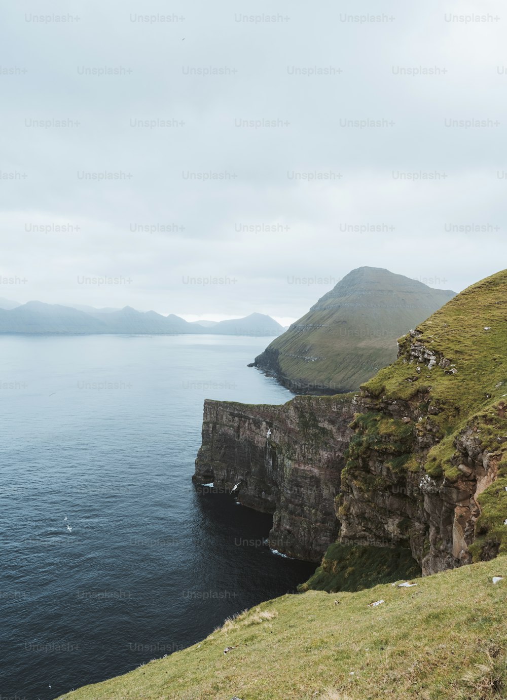 a large body of water sitting next to a lush green hillside