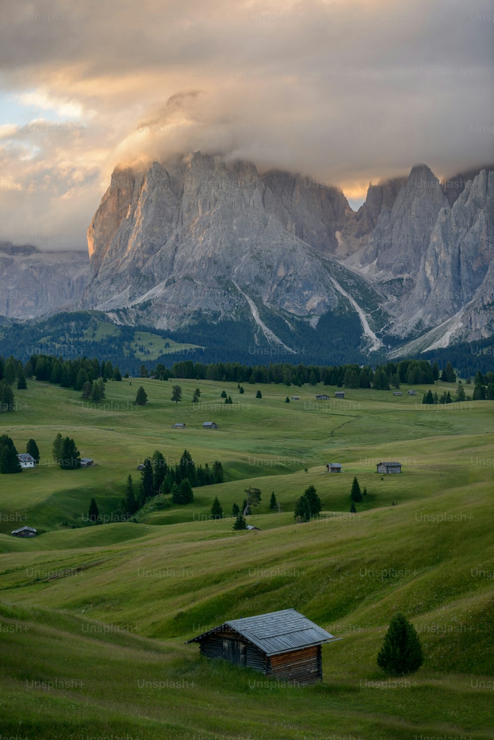 a small cabin in a field with mountains in the background