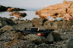 a fire pit sitting on top of a rocky beach