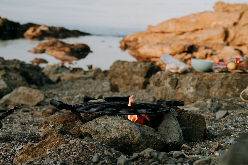 a fire pit sitting on top of a rocky beach