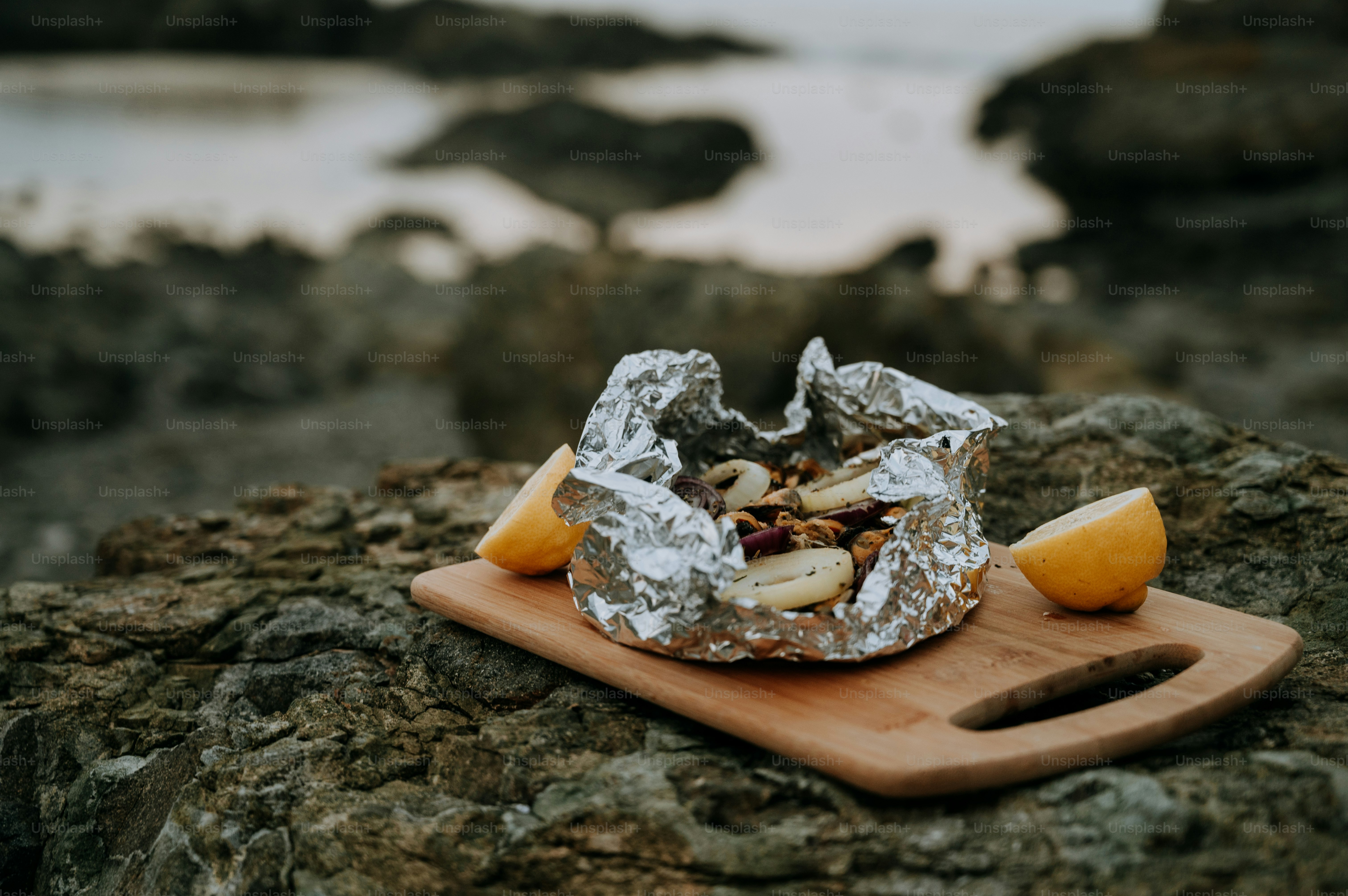 a wooden cutting board topped with food on top of a rock
