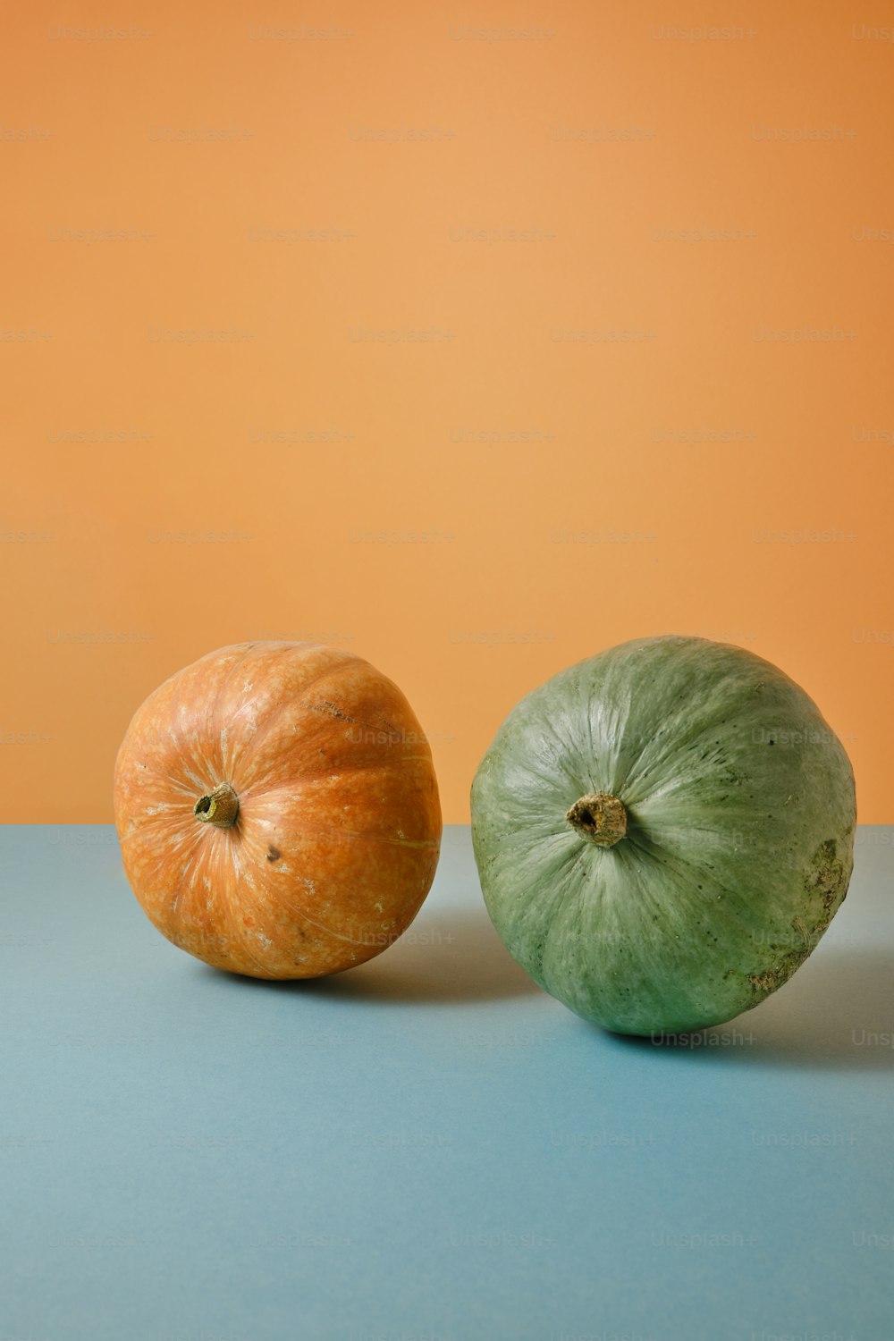 two oranges and a green apple on a blue surface