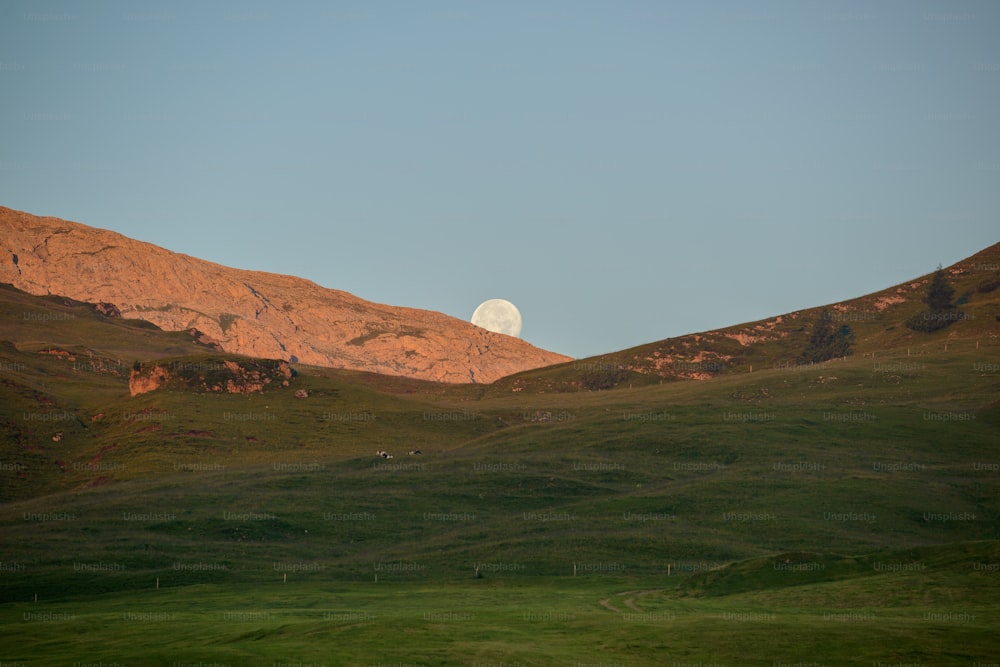 the moon is setting over the mountains in the distance