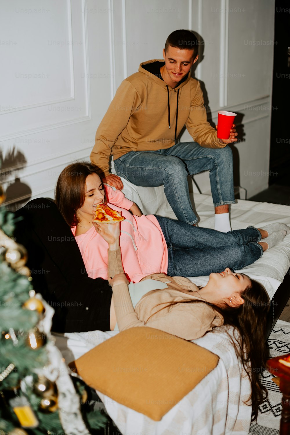 Un hombre y una mujer sentados en una cama comiendo pizza