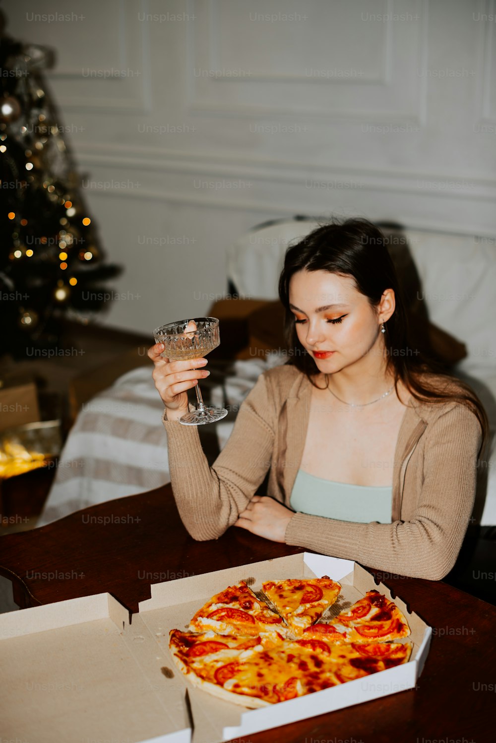 uma mulher sentada em uma mesa com uma pizza à sua frente