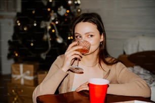 a woman sitting at a table drinking a glass of wine