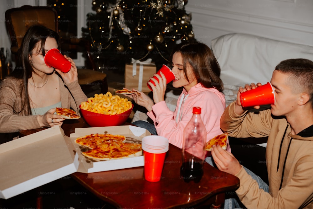 un groupe de personnes assises autour d’une table en train de manger une pizza