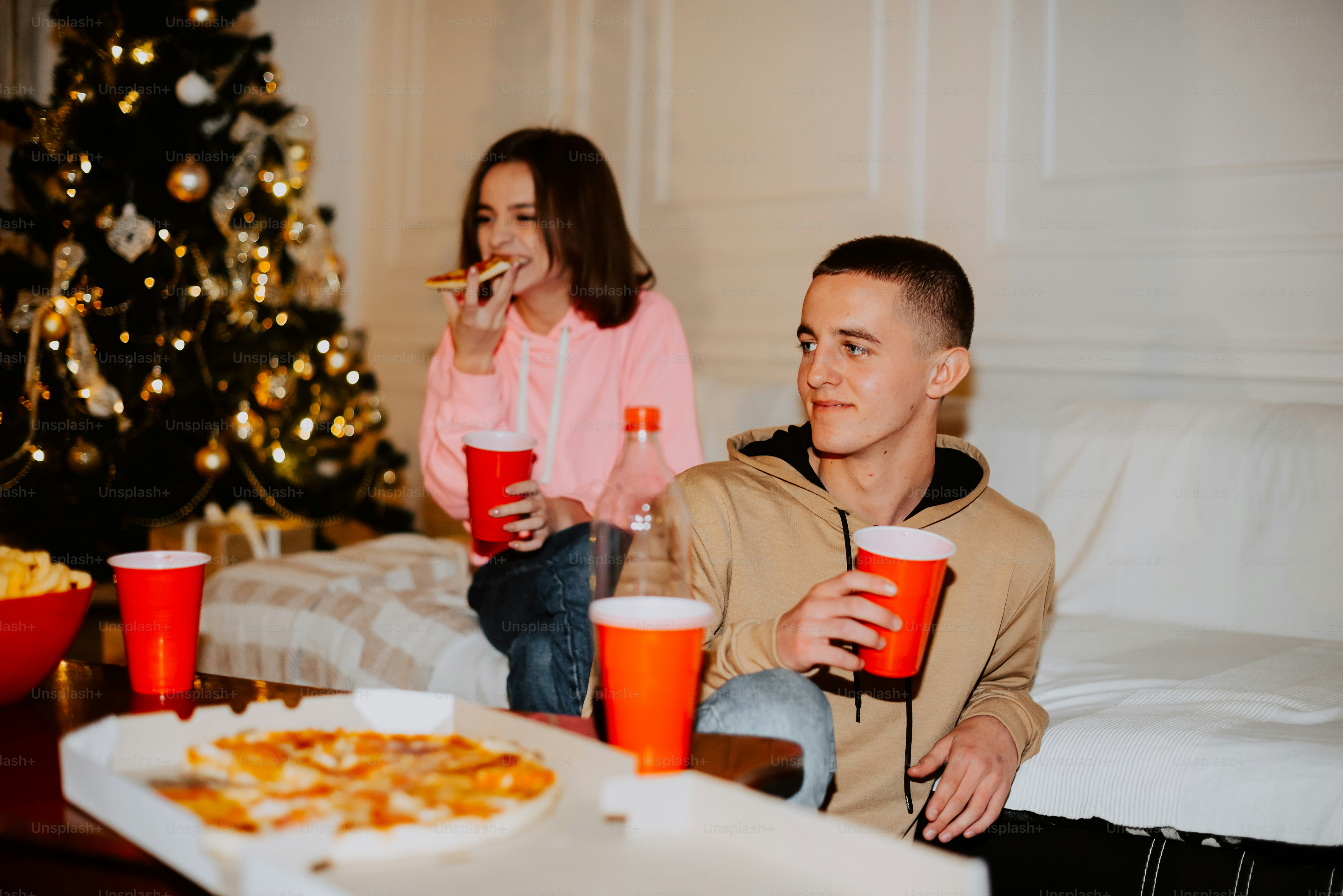 a man and a woman sitting on a couch eating pizza