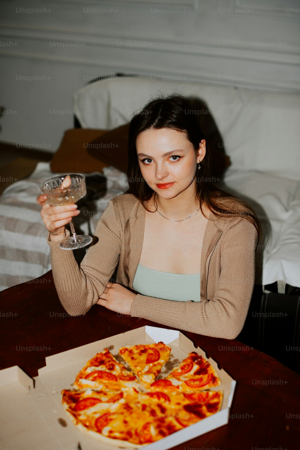 a woman sitting at a table with a pizza and a glass of wine