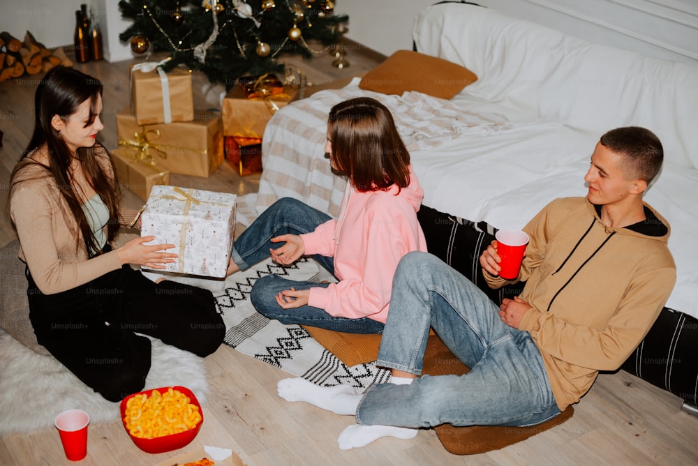 a man and a woman sitting on the floor near a christmas tree