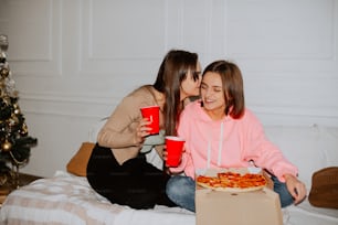 a couple of women sitting on top of a bed