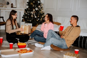 a group of people sitting on the floor with pizza and drinks