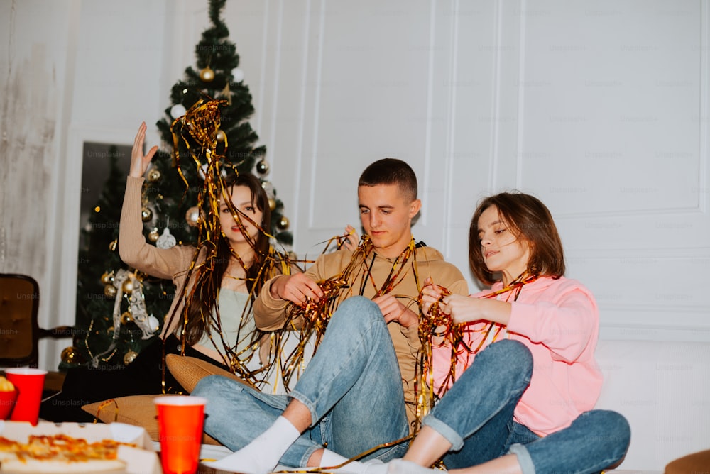 a man and a woman sitting on the floor next to a christmas tree