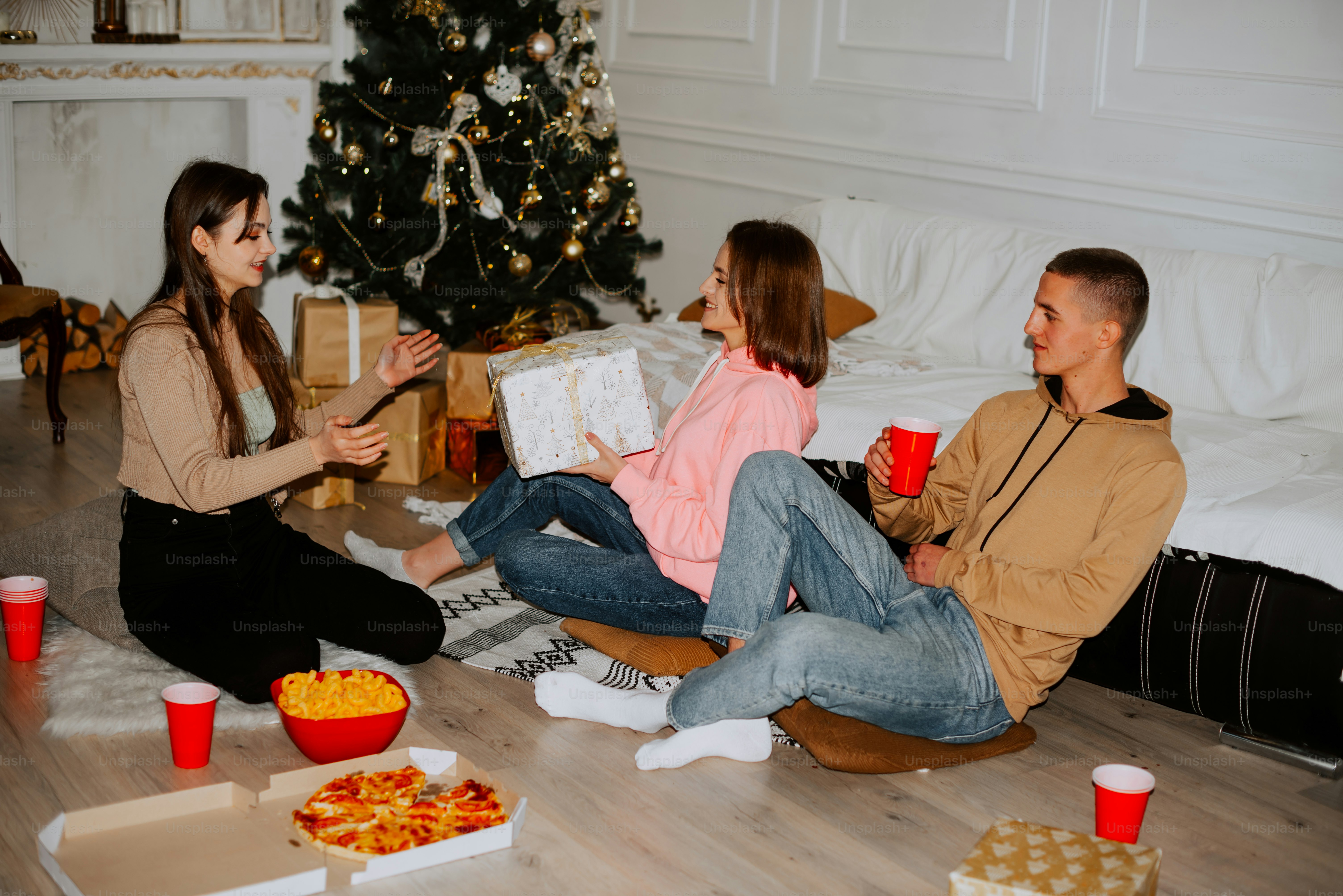 Ein Mann und eine Frau sitzen auf dem Boden in der Nähe eines Weihnachtsbaums
