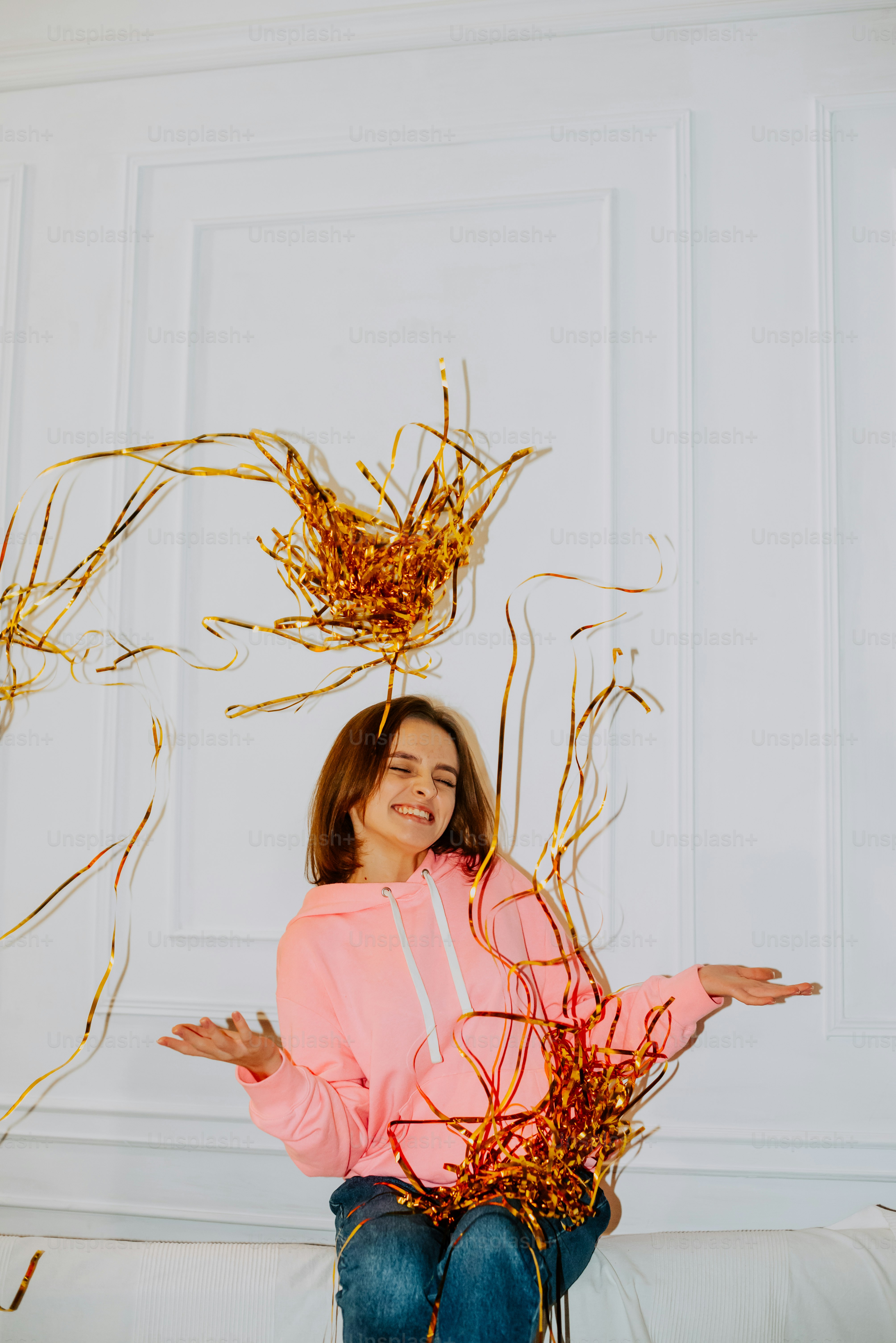 a woman sitting on a bed with a bunch of gold streamers